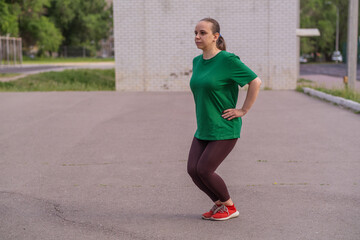 Young woman stretching in a green shirt during outdoor workout