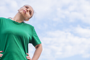 A woman stretching in a green shirt prepares for exercise in an urban park surrounded by buildings...