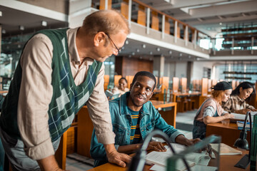 Professor helping a student in library with assignments