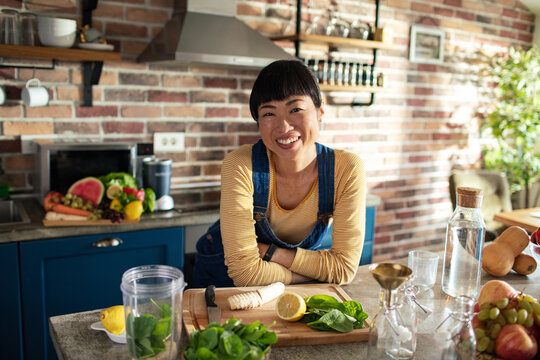 Portrait of a smiling female nutritionist in a modern kitchen filled with fruits and vegetables