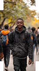 Fototapeta premium Young man smiles, walking outdoors amongst blurred figures on a fall day