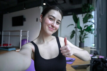 Smiling woman giving thumbs up during online home workout