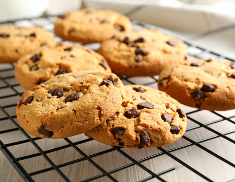 Warm chocolate chip cookies are piled on a cooling rack, their sweet aroma filling the air with nostalgic comfort.