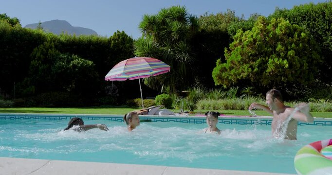 Holding hands by pool edge, Diverse friends leaping into water and rocking donut floats for fun