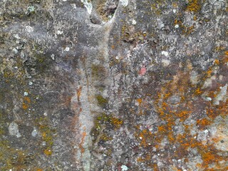 Close-up of a natural rock surface with a rough, uneven texture, visible cracks, and earthy tones,...