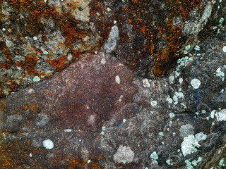 Close-up of a natural rock surface with a rough, uneven texture, visible cracks, and earthy tones,...