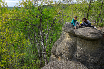 Teenager hikers are resting on the top of of rock structures, geological site, place of prehistoric...