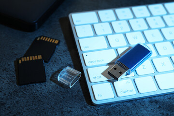 SD memory cards, USB flash drive and keyboard on dark grey table, closeup