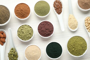 Different superfood powders on white wooden table, flat lay