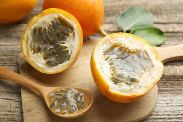 Ripe passion fruits, seeds and green leaves on wooden table, closeup