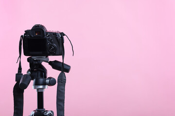 Modern professional video camera on pink background, space for text