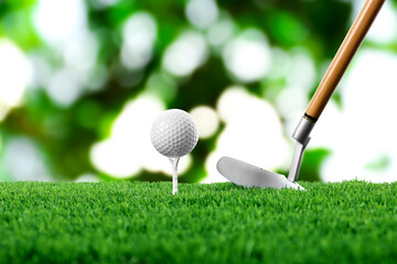 Golf ball on green grass and club outdoors, closeup