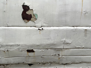 Sheet metal corrosion on an old white car. Corroded surface with a transverse stripe pattern. Damaged and pitted texture. Rusty background. Hole car body detail sheet. Holes in the car body.