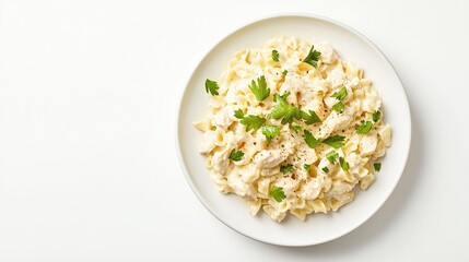 Creamy chicken pasta dish served on a white plate, garnished with fresh parsley, photographed against a white background from a high-angle perspective