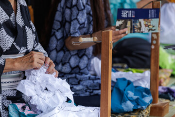 Artisan engages in tying cone shaped knots into fabric used in traditional Japanese...