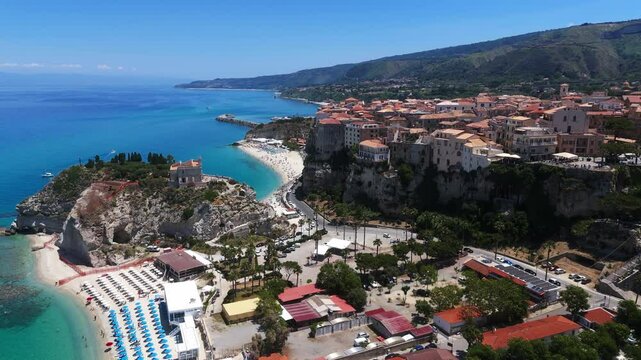 Aerial drone view of Tropea, Calabria, with its crystal clear turquoise waters, beaches, and the iconic Sanctuary of Santa Maria dell Isola perched on a cliff