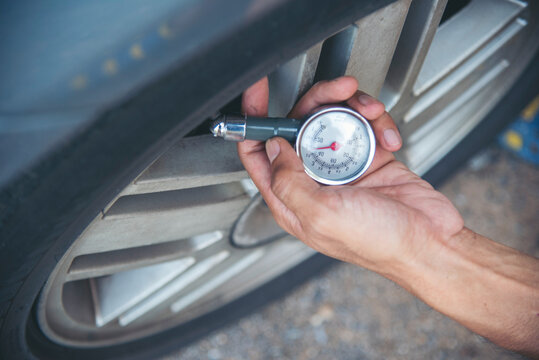 Fototapeta Mechanic man hands checking car tires outdoor on site service auto garage for automotive mobile center services. Technician workshop repair checking tyres car motor vehicles service mechanical hands