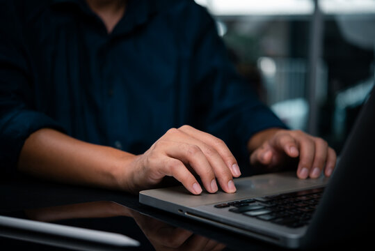 Close-up of hands typing on laptop in a dark workspace. Concept of work focus, remote job, or programming technology digital transformation, and smart work solutions.