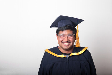 30-year-old dark-skinned Latino man with glasses wears a cap and gown to celebrate his graduation and end of school