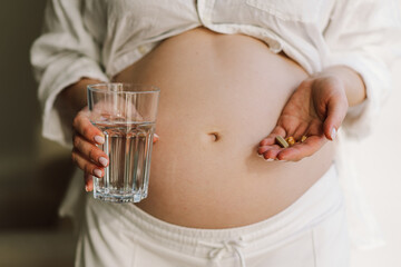 Pregnant young woman holding vitamins to maintain health of herself and her baby. Pregnancy and...