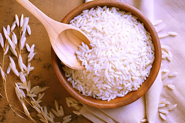Bird s eye view of wooden spoon with rice in wooden bowl on rice and rice ears background Protein rich natural food