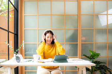 Young woman happy listen music for chill and relax after finish work.   Lifestyle girl using laptop for meeting and working  in living room at home.  Lifestyle Concept