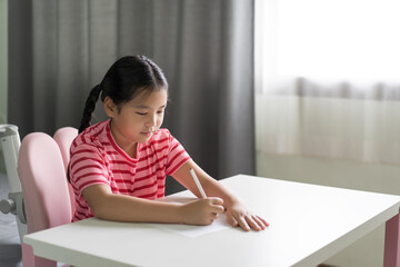 asian child learn from home or kid girl student smile writing on paper to draw learning studying or young people enjoy fun doing homework and write in classroom homeschool on white table or desk