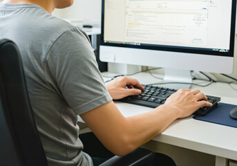 PCに向かって座っている人の背中
