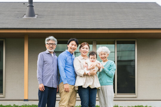 住宅の前に並ぶ三世代家族の集合写真