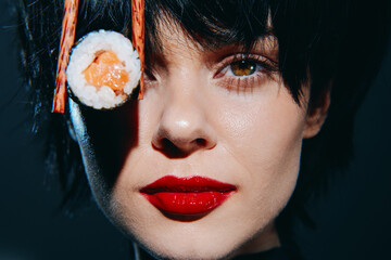 Close-up portrait of a young woman with bold red lips and sushi on her eye, showcasing modern...