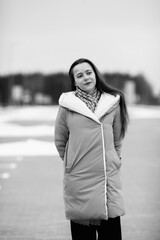 Fototapeta premium Portrait of a young beautiful dark-haired girl outdoors in winter. Black and white photo.