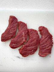 Raw beef steak presented on a white surface