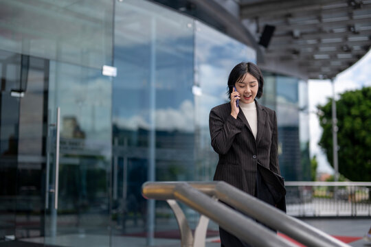 A woman is talking on her cell phone while walking down a sidewalk - Powered by Adobe