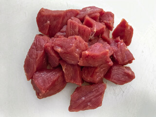 Glossy, fresh beef cubes with rich red tones, arranged invitingly on white