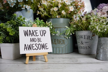 Wake up and Awesome text on paper card with flowers decoration on wooden background