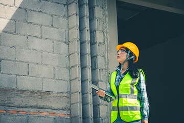 Worker holds computer displaying construction plan while assessing project quality onsite.