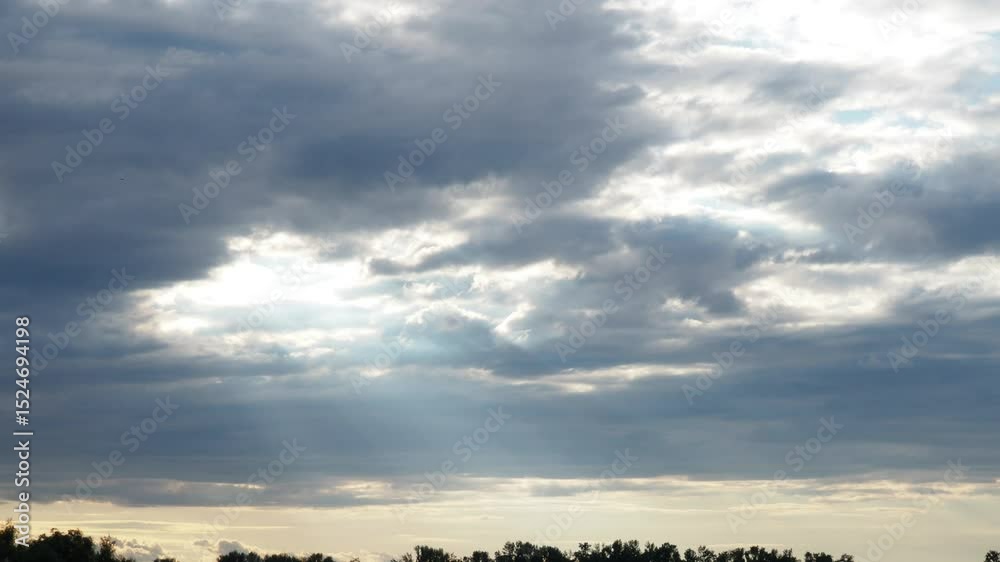 Poster Witness the captivating journey of light slicing through layered clouds during twilight, showcasing natures artistry in a serene landscape. A transformative display unfolds overhead. Quick time lapse