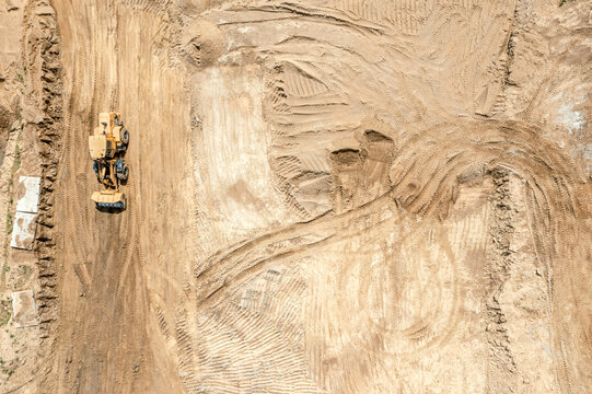 heavy earthmover working at earthworks at a construction site. flattening ground. aerial top view.