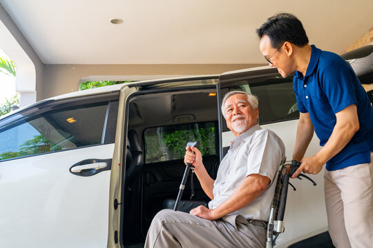 Asian man caregiver or taxi driver helping senior man patient get in the car to get to medical appointments or healthcare therapy sessions at hospital. Assisted elderly patient transportation services - Powered by Adobe