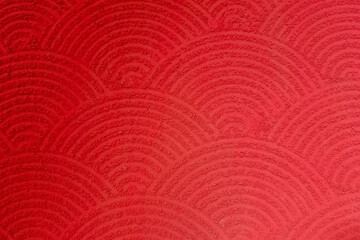 Red textured surface with repeating semi-circular wave patterns, resembling traditional Japanese motifs.