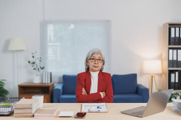 Confident senior businesswoman sitting with arms crossed at her desk in the office, demonstrating...