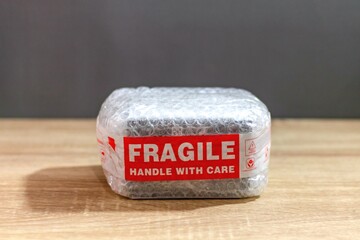 A package box wrapped in bubble wrap and sticky tape marked Fragile