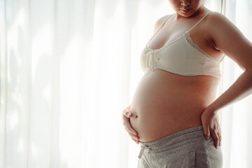 4K Young happy pregnant woman posing in studio with white curtains in background