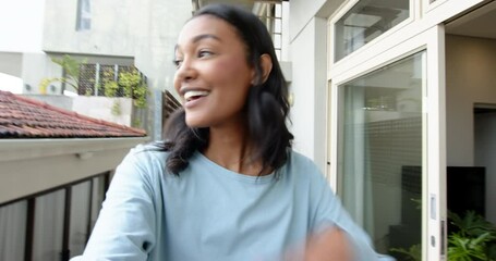 Grabbing camera, Asian woman stepping onto balcony filming city view and greeting viewers