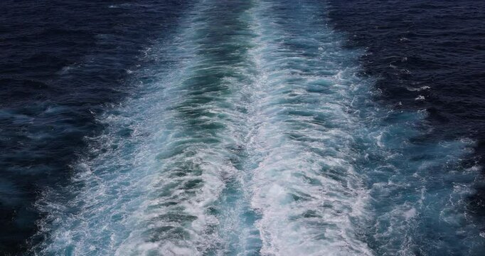 Pacific blue ocean wake behing cruise ship. Destination vacation travel tropical ocean sea. Caribbean cruise. Beautiful blue Ocean water. Powerful propeller wash and fluid dynamic cause a pattern.