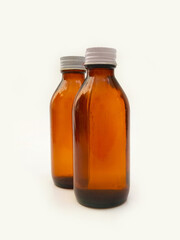 Amber glass bottles with an aluminum cap isolated on a white background, 2 brown glass bottles for pharmaceuticals, syrups, essential oils, and cosmetics