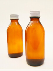Amber glass bottles with an aluminum cap isolated on a white background, 2 brown glass bottles for pharmaceuticals, syrups, essential oils, and cosmetics