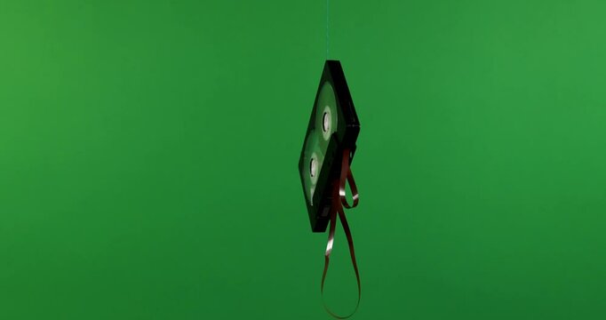 A VHS tape appears suspended against a vibrant green backdrop, showcasing nostalgia and retro themes.