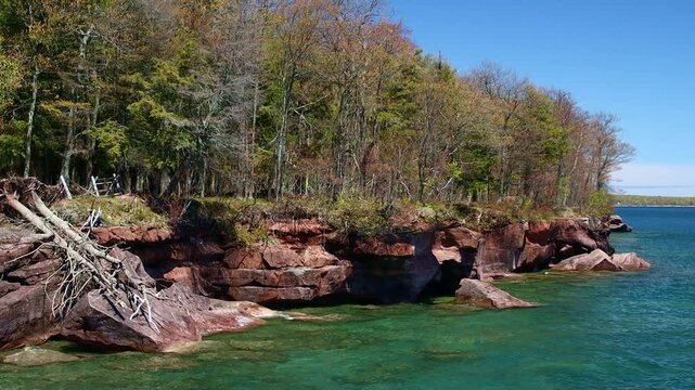 A breathtaking view of Madeline Island Lake Superior shoreline, with crystal-clear turquoise water, rocks, and vibrant spring trees, perfect for a scenic getaway