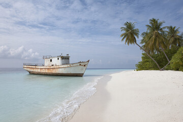 Obraz premium abandoned vessel resting on pristine maldivian beach surrounded by crystalclear waters and soft white sand